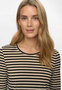 Langarmshirt met horizontale zwarte en beige strepen, voorzien van een ronde hals. Zacht materiaal en een gladde textuur zijn duidelijk zichtbaar.