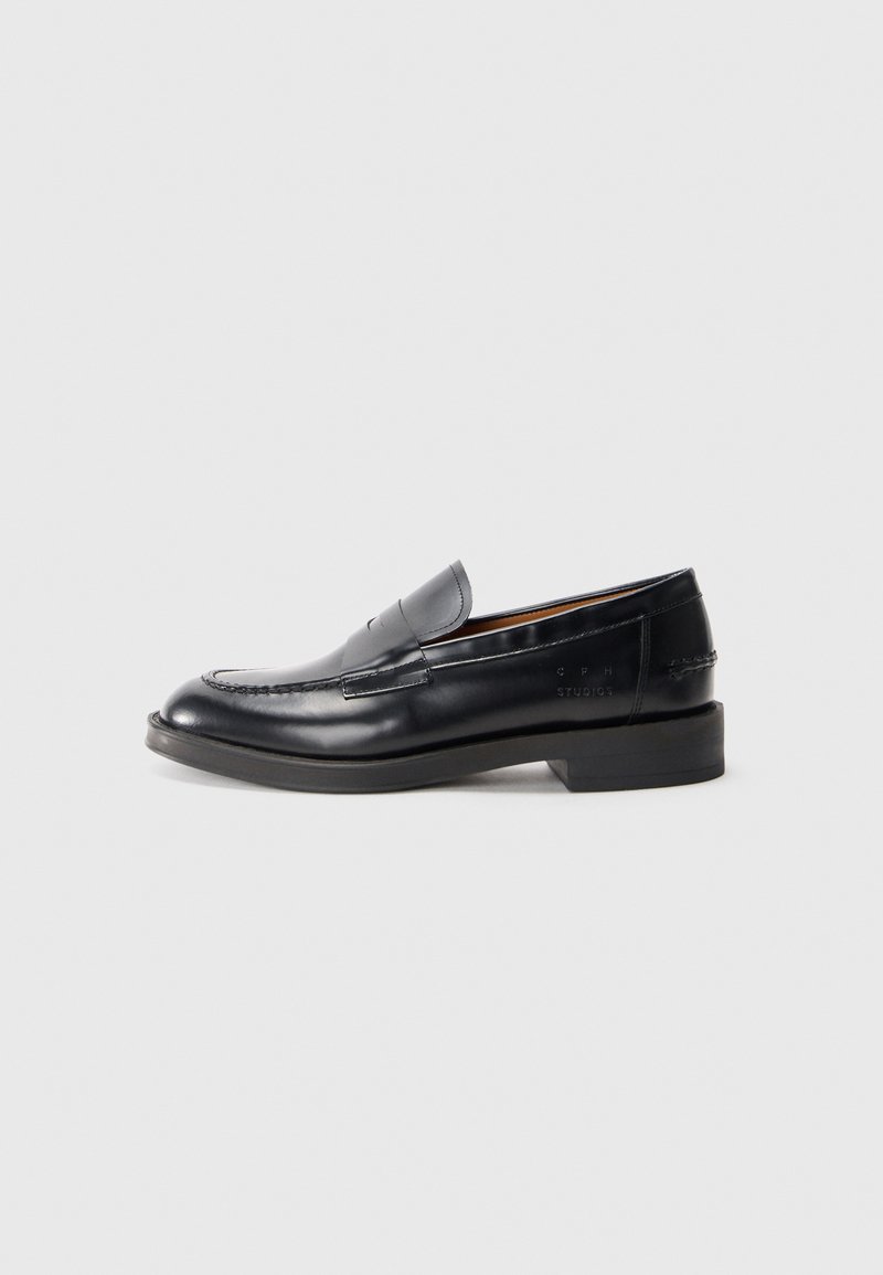 Mocassins en cuir noir avec un design cousu, bout rond, talon bas empilé et détail de logo estampé sur le côté. Texture lisse.