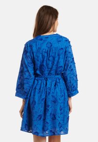 Blue embroidered dress with floral patterns, three-quarter sleeves, belted waist, and textured fabric.  Mid-thigh length and relaxed fit.