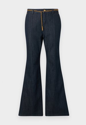 Jean flare en denim foncé avec taille haute, ornés d'une ceinture en chaîne dorée et de surpiqûres contrastantes le long des coutures.