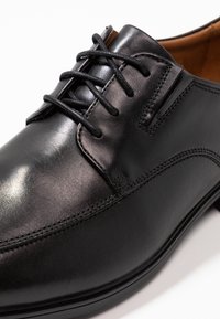 Zwarte leren derbyschoen met een ronde neus, veters en subtiele stikdetails. Gladde textuur met gepolijst afwerking. Klassiek ontwerp.