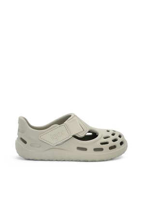 Hellgrauer Schlupfschuh mit belüfteten Löchern, verstellbarem Klettverschluss und flexibler Sohle, entworfen für Komfort und Atmungsaktivität.