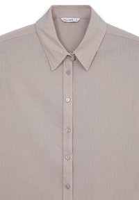 Camicia button-up beige chiaro realizzata in tessuto testurizzato. Presenta un colletto a punte e otto bottoni abbinati lungo la parte anteriore.