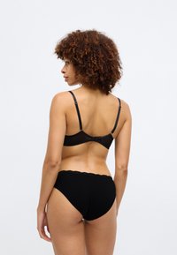 Μαύρο σετ εσωρούχων που περιλαμβάνει ένα διάφανο σουτιέν με μαλακές cups, ρυθμιζόμενους ιμάντες και κούμπωμα, μαζί με μαύρα ψηλόμεσα εσώρουχα με δαντέλα.