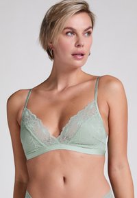 Mintgroene kanten bralette met bloemenpatronen, een driehoekig cupontwerp, verstelbare bandjes en een zachte stoffen band eronder.
