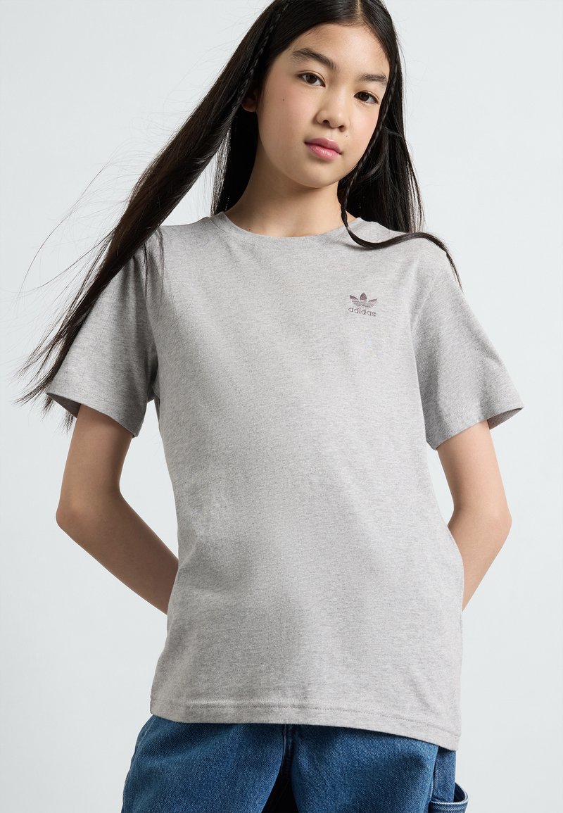 Gray cotton t-shirt with short sleeves, featuring a small Adidas logo on the chest. Smooth texture and relaxed fit, paired with blue denim.