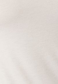 Lichtbeige stof met een gladde textuur en subtiel geribbeld patroon. Het materiaal lijkt rekbaar en lichtgewicht, geschikt voor casual kleding.
