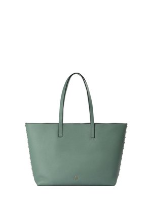 Bolso tote de cuero verde con doble asa y pequeño emblema metálico de calavera centrado cerca de la parte inferior frontal.