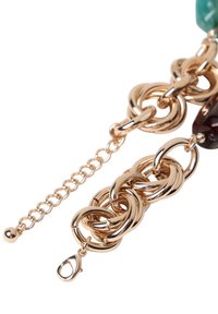 Bracciale in metallo dorato con link rotondi intrecciati, chiusura a moschettone e bead decorativi nei colori verde e rosso scuro.