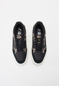 Schwarze Sneakers mit einem Schlangenmuster, schwarzen Wildleder-Akzenten, flachen Schnürsenkeln, perforierter Zehenpartie und weißer Gummisohle.