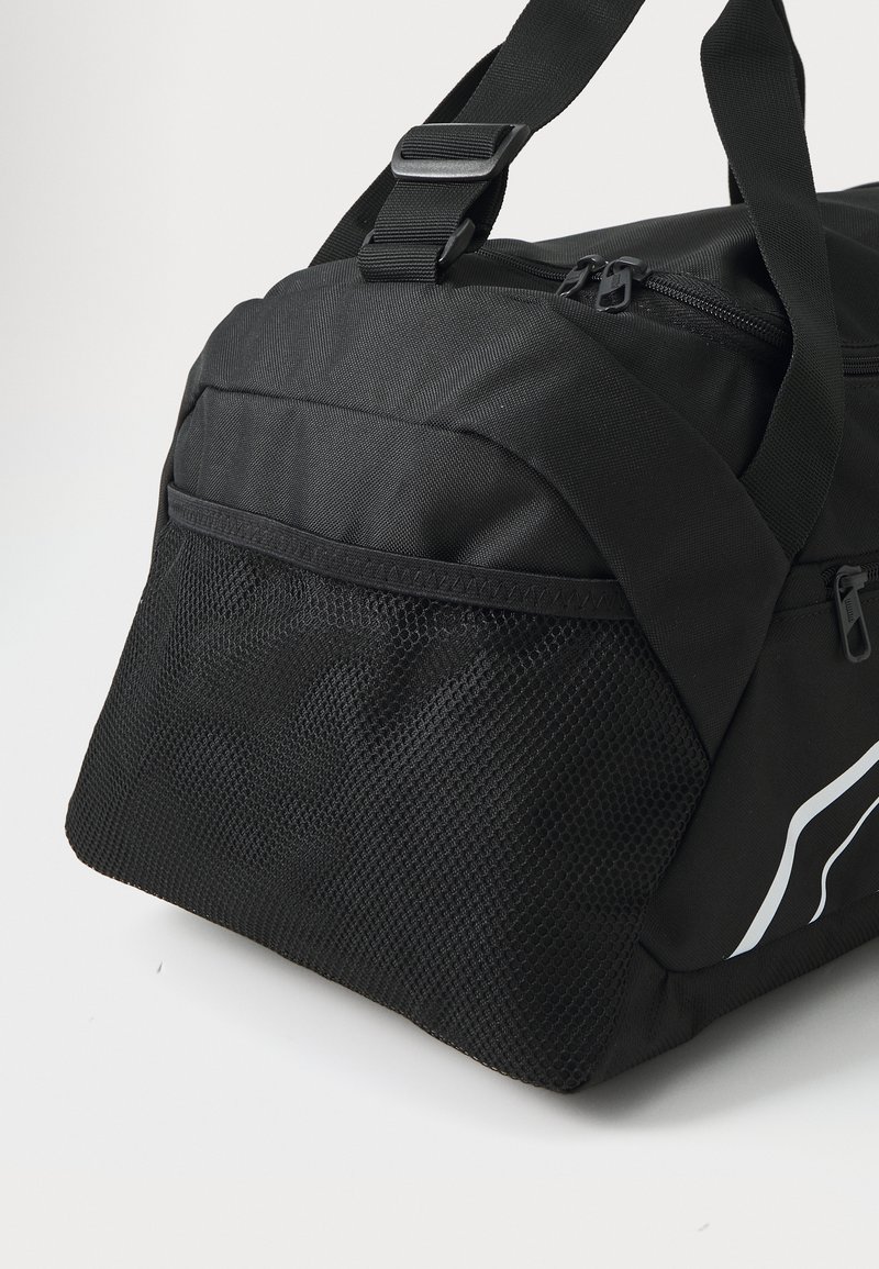 Sac de sport noir en tissu durable, avec une poche latérale en maille, un compartiment principal zippé et des sangles réglables. Texture lisse.
