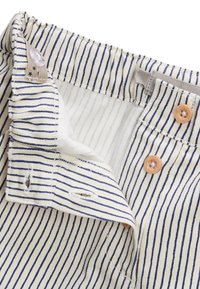 Shorts en tissu rayé avec des rayures verticales beige et marine, comportant des boutons en bois, une taille cousue et une doublure douce au toucher.