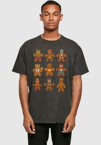 Camiseta de algodón gris oscuro con diseños coloridos de superhéroes de jengibre. Corte holgado con mangas cortas y cuello redondo acanalado.