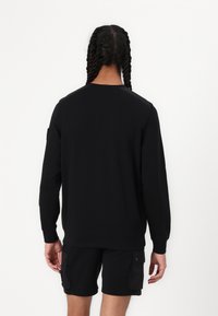 Sorte sweatshirt med lange ærmer og ribbede manchetter. Har en rund halsudskæring og en glat tekstur. Ingen synlige logoer eller mønstre.