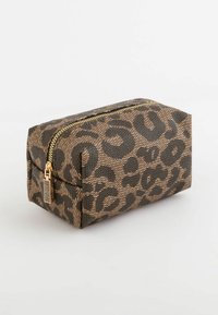 Trousse de maquillage en imprimé léopard, fabriquée en tissu texturé, avec une fermeture éclair dorée et une forme rectangulaire aux côtés renforcés.