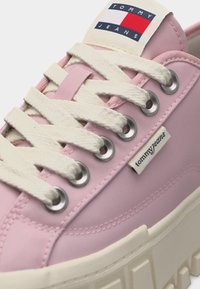 Ροζ αθλητικό παπούτσι Tommy Jeans με χοντρές λευκές κορδόνες, μεταλλικά κρίκους, υφασμάτινη ετικέτα με λογότυπο και χοντρή εκρού σόλα.