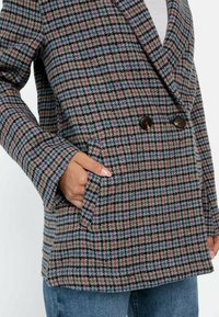 Geruite dubbel-breasted jas in bruin, blauw en roze. Voorzien van brede revers, zijzakken en een geweven wolmix stof.