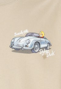 Camiseta beige con un coche clásico de dibujos animados en azul claro, con un personaje sonriente en su interior, y el texto "Beverly Hills" y "Dylan Duck".