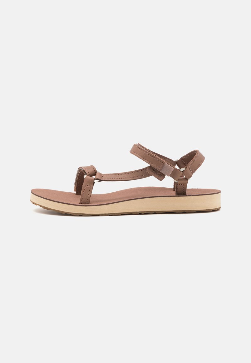Brown flat sandals featuring adjustable straps, a cushioned footbed, and a contrasting light beige sole with textured detailing.