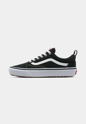 Schwarze Leinensneaker mit weißen Akzenten, abgerundeter Zehenpartie und dicker weißer Zwischensohle. Schnürsenkel in Silber mit einer roten Lasche an der Ferse.