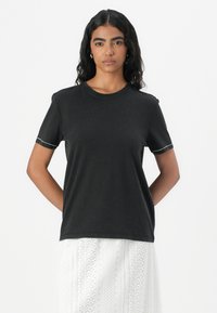 T-shirt en coton noir à manches courtes, col rond, avec des détails de couture contrastés au niveau des poignets. Texture lisse, coupe décontractée.