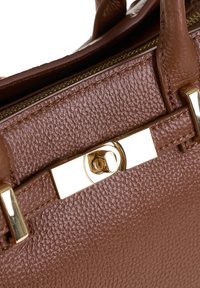 Borsa a tracolla in pelle marrone con finitura testurizzata, dotata di una chiusura a scatto rettangolare in tono oro e manici cuciti visibili sopra la zip.