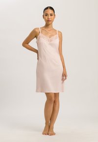 Caminetto rosa pallido con dettagli in pizzo lungo lo scollo, spalline regolabili e una texture liscia e morbida, che arriva sopra il ginocchio.