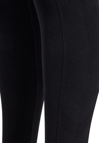 Svarta leggings med en texturerad vertikal chevronmönster. Tillverkade av stretchigt tyg för komfort, med en slät yta och figurnära design.
