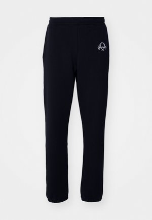 Black sweatpants made of a soft fabric with an elastic waistband, featuring side pockets and a small embroidered design on the left leg.
