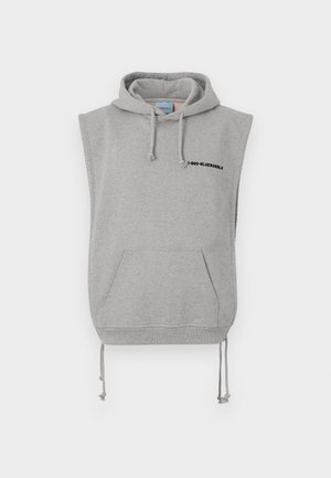 Haaleta hall kappa, mis on valmistatud puuvilla segumaterjalist. Sellel on esikott, reguleeritavad nöörid ja must trükitud tekst kaela lähedal.