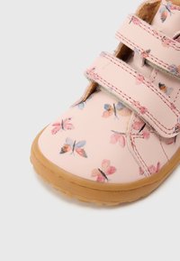 Roosa lasteking liblikatrükiga, takjakinnitustega, kummist tallaga ja siledast nahast pealiskihiga. Omab ümarat nina ja tekstuuriga detaile.