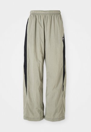 Pantaloni leggeri e larghi di colore grigio chiaro con pannelli laterali neri. Presentano una vita elasticizzata e un tessuto liscio e testurizzato.