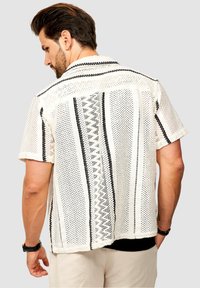 Kurzärmliges, weißes Hemd mit schwarzen vertikalen Streifen und strukturiertem Stoff. Verfügt über eine lockere Passform und ein Kentkragen-Design.