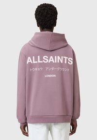 Felpa rosa polveroso con un grande logo bianco "ALLSAINTS" e testo giapponese sul retro. Presenta una vestibilità comoda e cappuccio con coulisse.