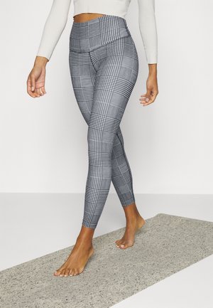 Leggings de sport noir et blanc à motif avec une taille haute, présentant des designs géométriques variés et un tissu lisse et extensible.