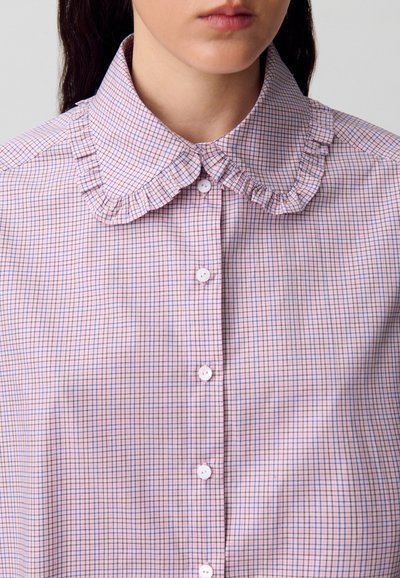 Camisa a cuadros en tonos rosa claro y azul con cuello con volantes, presenta botones blancos y una textura suave. Diseño con frente abotonado.