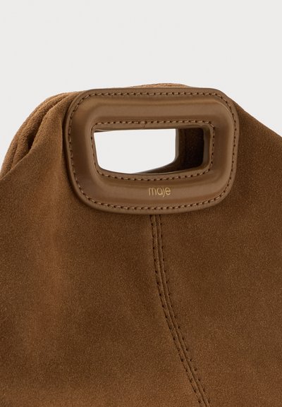 Sac en daim marron doux avec poignée en cuir rectangulaire présentant des bords cousus et logo "maje" embossé sur le cuir.