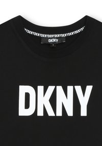 Svart bomull t-shirt med en stor vit "DKNY" logotyp på framsidan och ett upprepande logotypmönster inuti kragen.