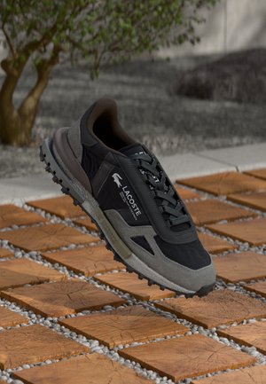 Sneaker Lacoste in nero e grigio, con un design in materiali misti caratterizzato da una parte superiore testurizzata, lacci e una suola robusta per una migliore trazione.