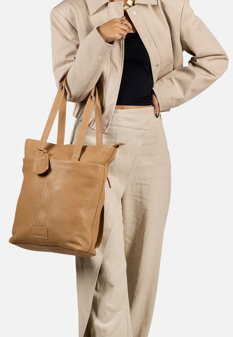 Borsa tote in pelle marrone con doppio manico, forma rettangolare, superficie testurizzata e chiusura a patta. Logo mostrato sul davanti.