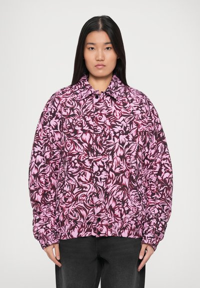 Doudoune imprimée florale rose et noire avec un col, fermeture à boutons et poignets élastiques, présentant une coupe ample et une texture matelassée.
