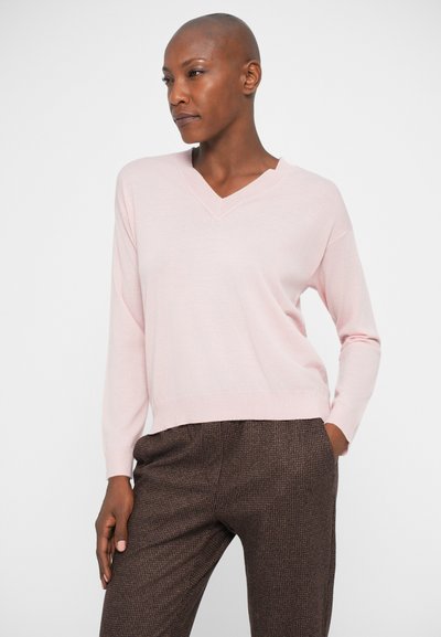 Pulover roz deschis cu guler în V, cu mâneci lungi, realizat din material moale, asortat cu pantaloni cu model texturat în tonuri de brown. Design simplu și minimal.