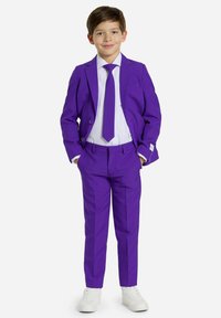 Traje morado con solapa muesca, dos botones y pantalones planos. Combinado con una camisa blanca y una corbata morada, terminado con zapatillas blancas.