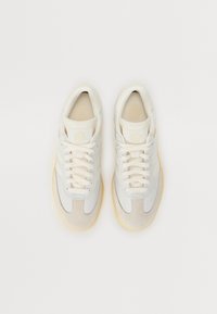 Light gray sneakers featuring a mix of leather and mesh, beige accents, round toe, and a textured rubber sole with gum detailing.