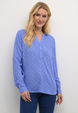 Lichtblauwe blouse met lange mouwen en een V-hals, voorzien van witte stippen en een knoopsluiting. Zachte stof met een ontspannen pasvorm.