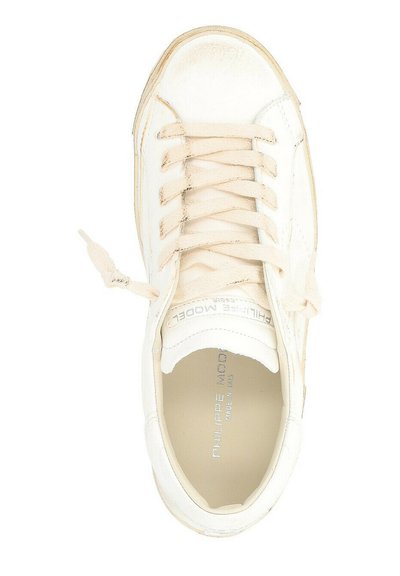 Sneaker in pelle bianca con punta arrotondata, lacci beige e marchio argentato sulla linguetta. Margini leggermente consumati e interno liscio.