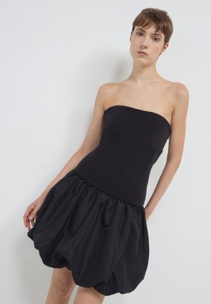 Robe noire sans bretelles avec un corsage ajusté et une jupe volumineuse froncée au toucher lisse.