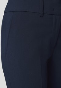 Granatowe spodnie o dopasowanym kroju z gładkiej tkaniny, z bocznymi kieszeniami i dopasowaną talią, wykonane z lekkiego materiału.