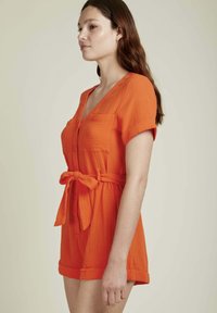 Robe courte orange en tissu texturé ; présente un décolleté en V, des manches courtes, des boutons sur le devant et une ceinture nouée à la taille.