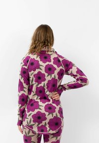 Langärmliges Oberteil in hellem Beige mit großem lila Blumenmuster und grünen Blättern. Verfügt über einen Stehkragen und eine figurbetonte Silhouette.